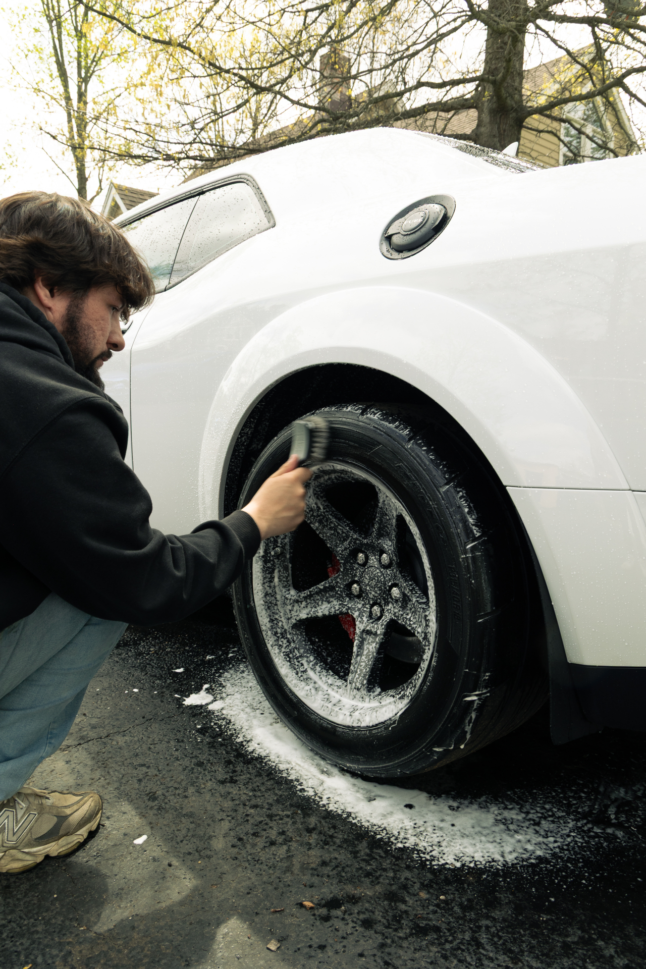 Detailer foam-scrubbing a wheel